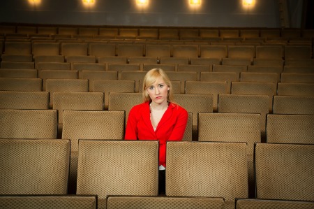 Single woman sitting lonely in an empty cinema or theatre